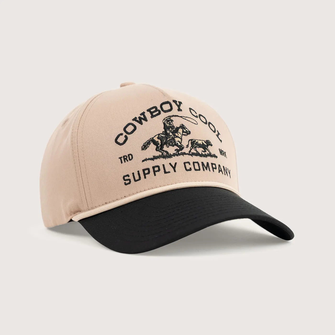 The Roper Hat in tan and black western cap with 'Cowboy Cool Supply Company' embroidered text and a calf roping logo on a light gray background