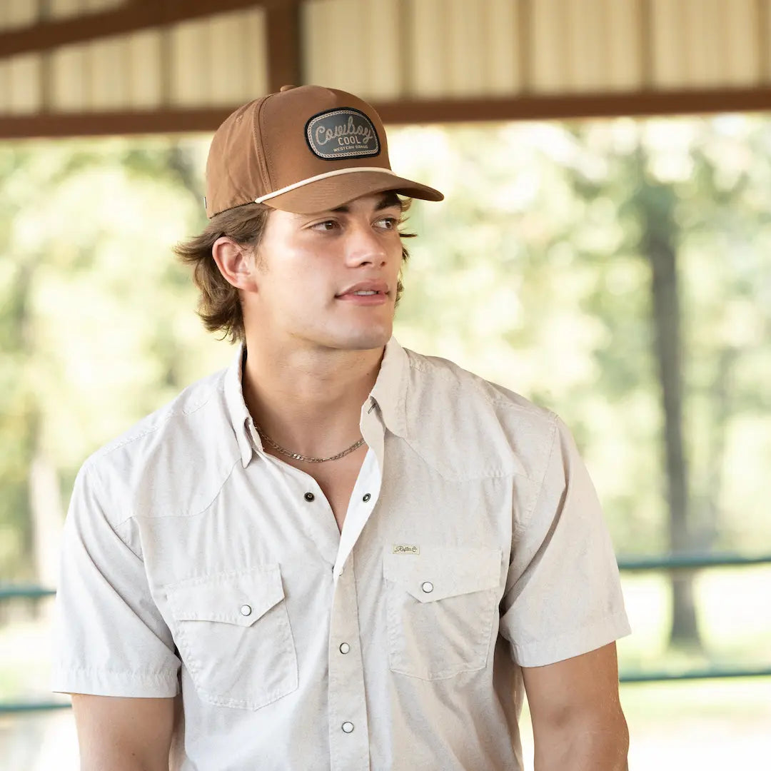 Man wearing a brown western cap and light shirt outdoors