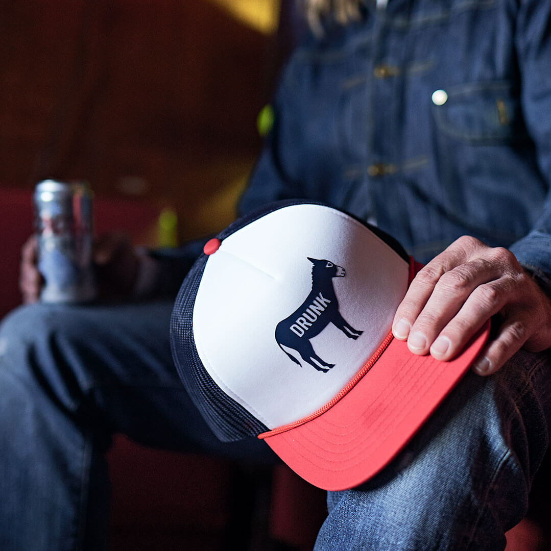 Close up of Cowboy Cool Drunk Ass Hat and a man holding a beer