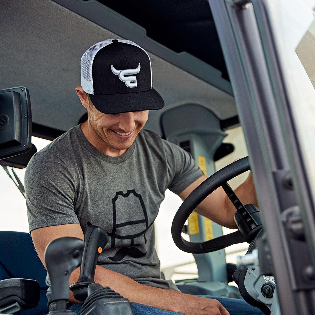 Man in tractor wearing Cowboy Cool El Toro Snapback hat.