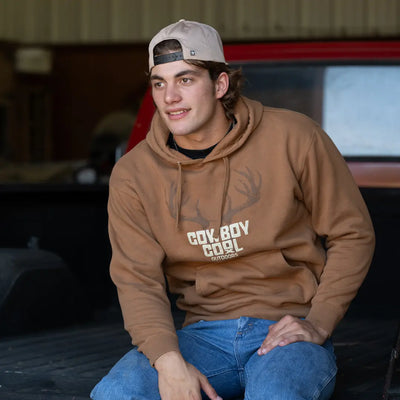 Brown western hoodie with 'Cowboy Cool Outdoors' graphic with a deer skull on a light beige background