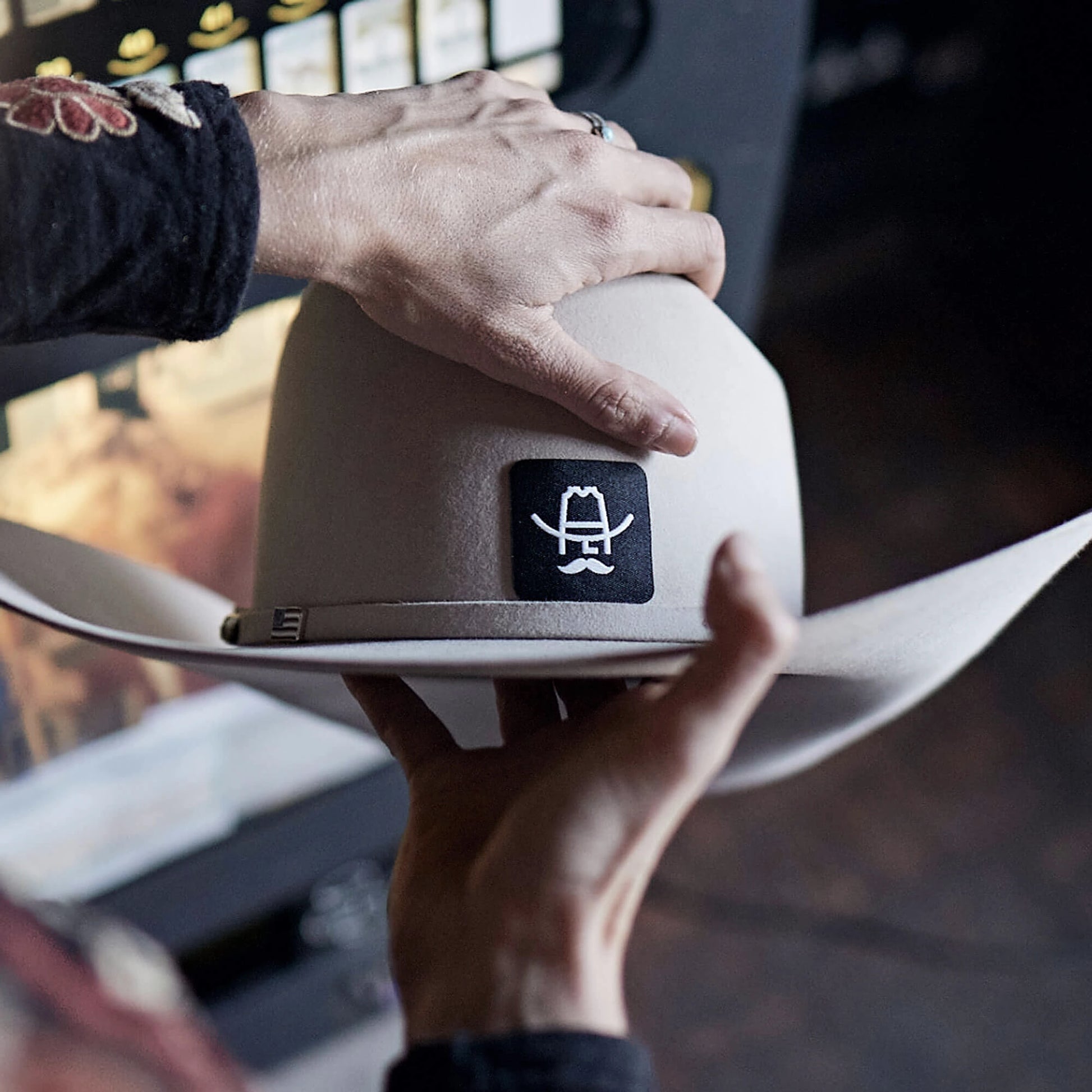 Cowboy Hat Patch Sticker shown on light gray cowboy hat, featuring black patch with white embroidered logo