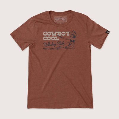 Cowboy Cool Whiskey Club T-Shirt in heather clay, featuring a retro-style western cowgirl with pistol graphic and 'Marfa, Texas' lettering on the chest.