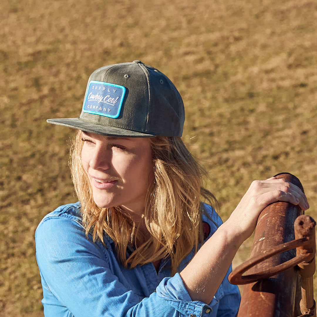 Woman opening a gate wearing a Cowboy Cool Houlihan Hat in Olive. 
